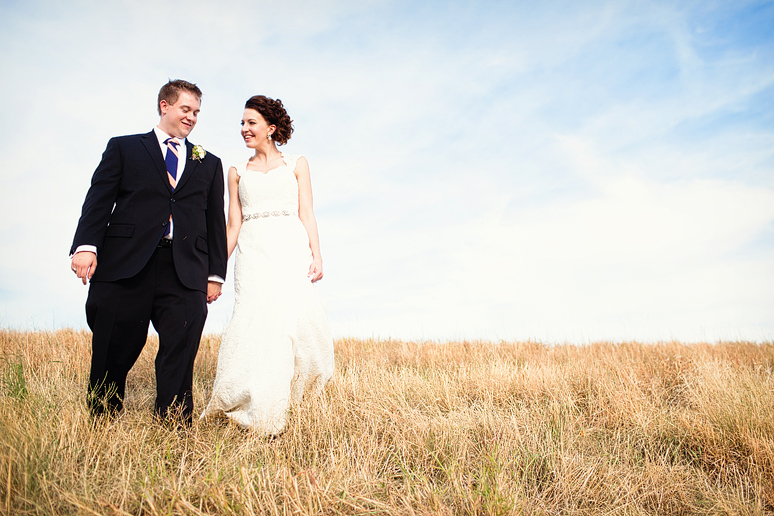 bride and groom walking down a hill with tall grass by Dallas wedding photographer Allison Davis Photography
